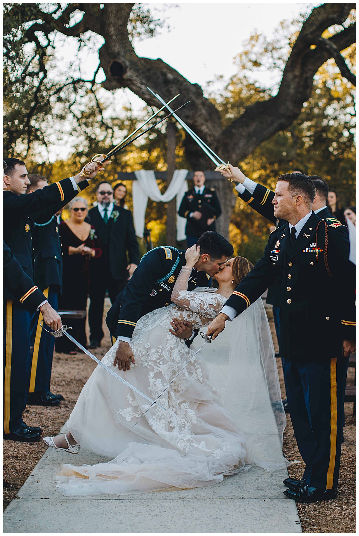 saber arch and bride and groom kiss during wedding ceremony