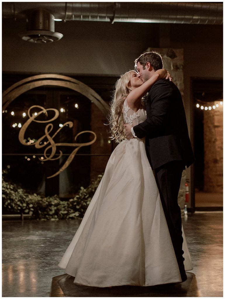 bride and groom dancing in front of custom monogram in circle arch