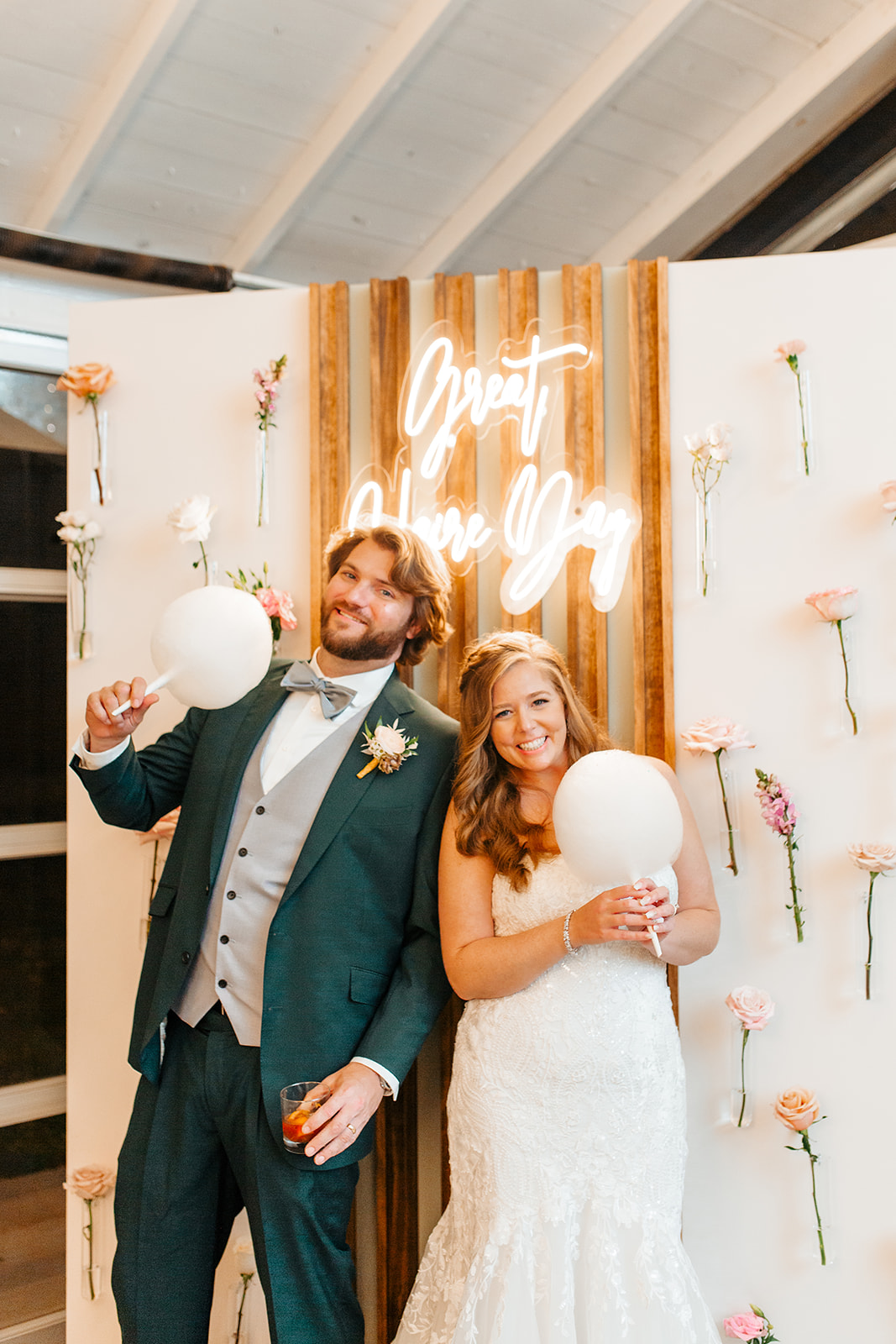 photo backdrop with neon sign, bride and groom cotton candy