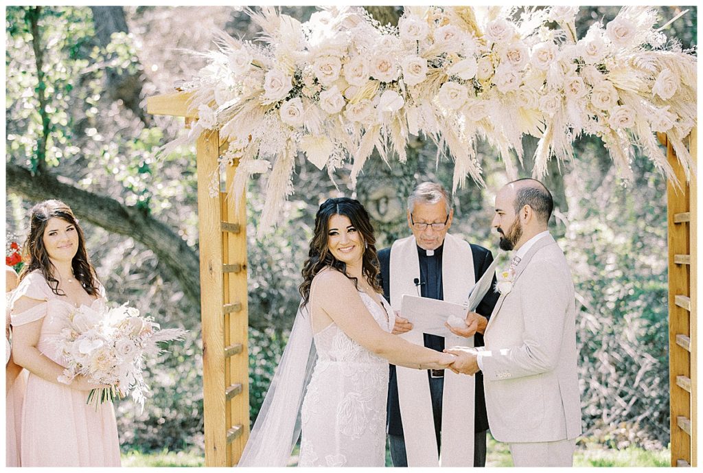 bride and groom standing under boho alter for ceremony